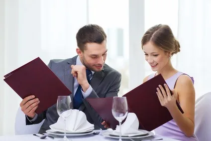 smiling couple with menus at restaurant